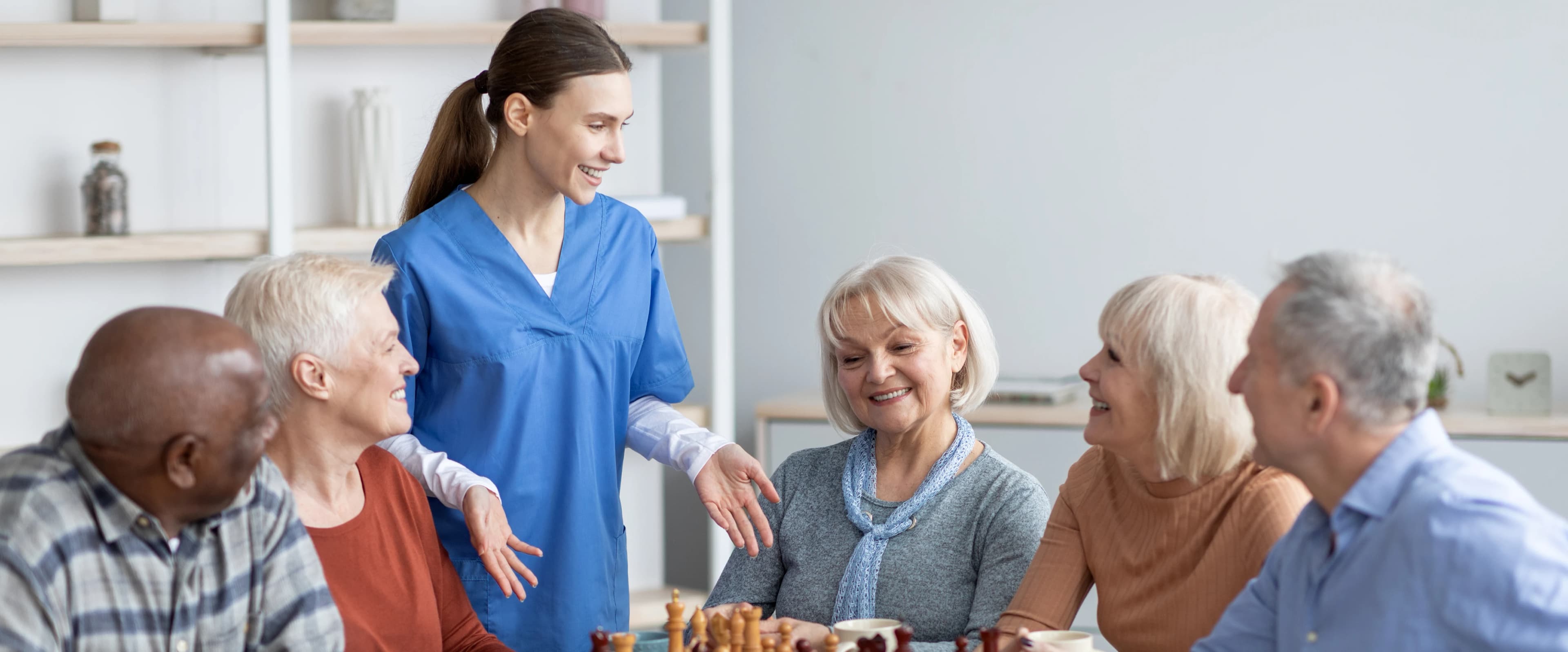 Krankenschwester mit einer Gruppe älterer Menschen beim Schachspielen