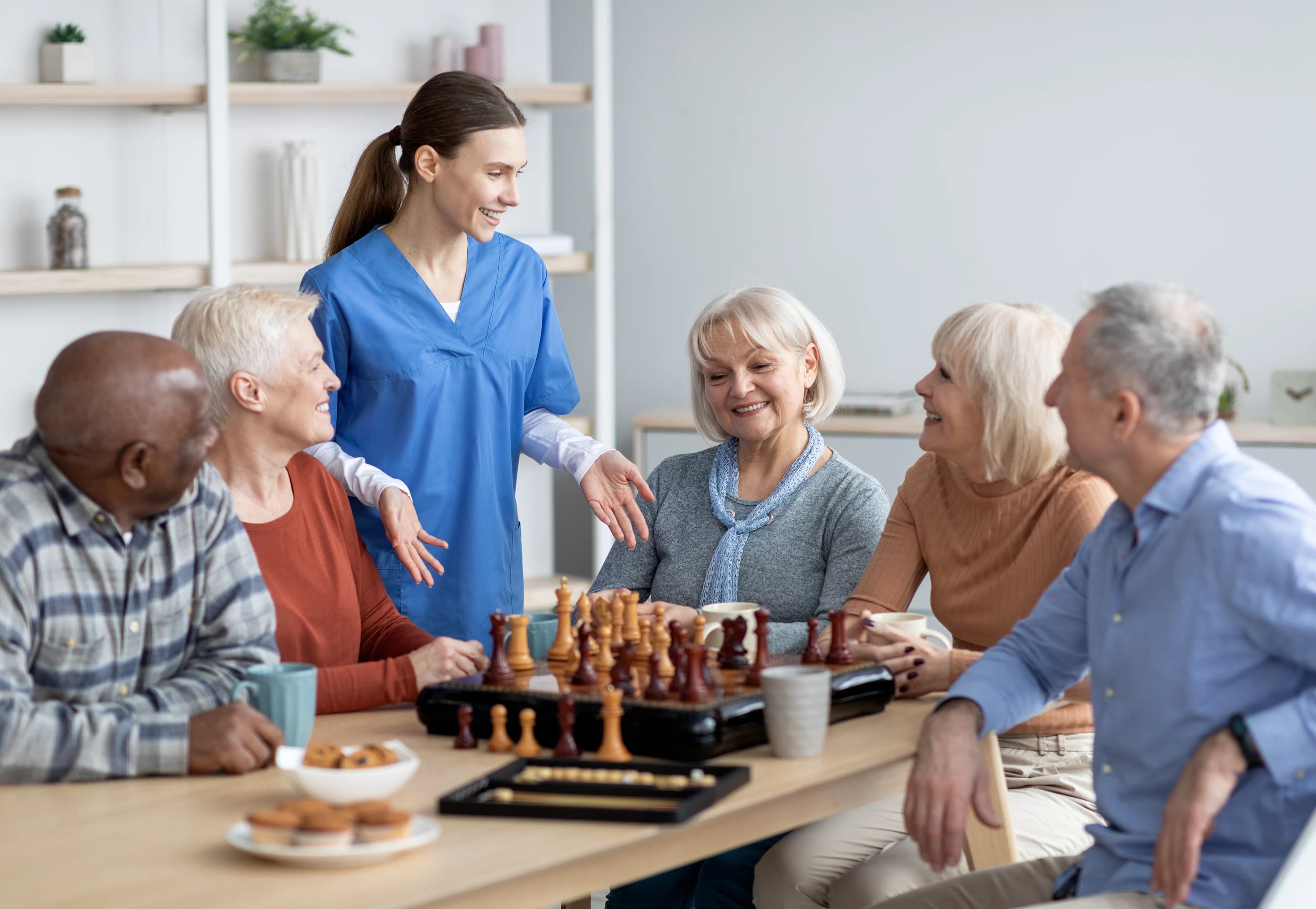 Krankenschwester mit einer Gruppe älterer Menschen beim Schachspielen